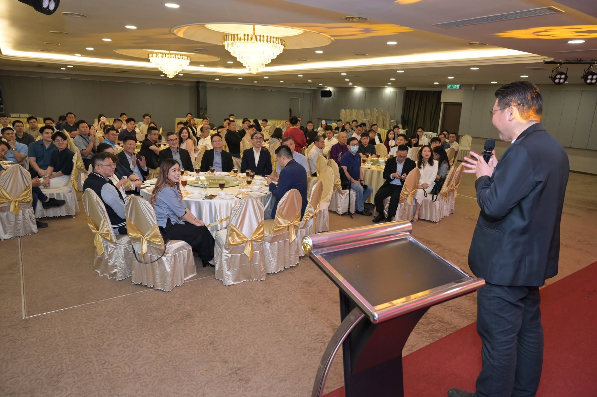 A speaker addressing members from a ballroom rostrum