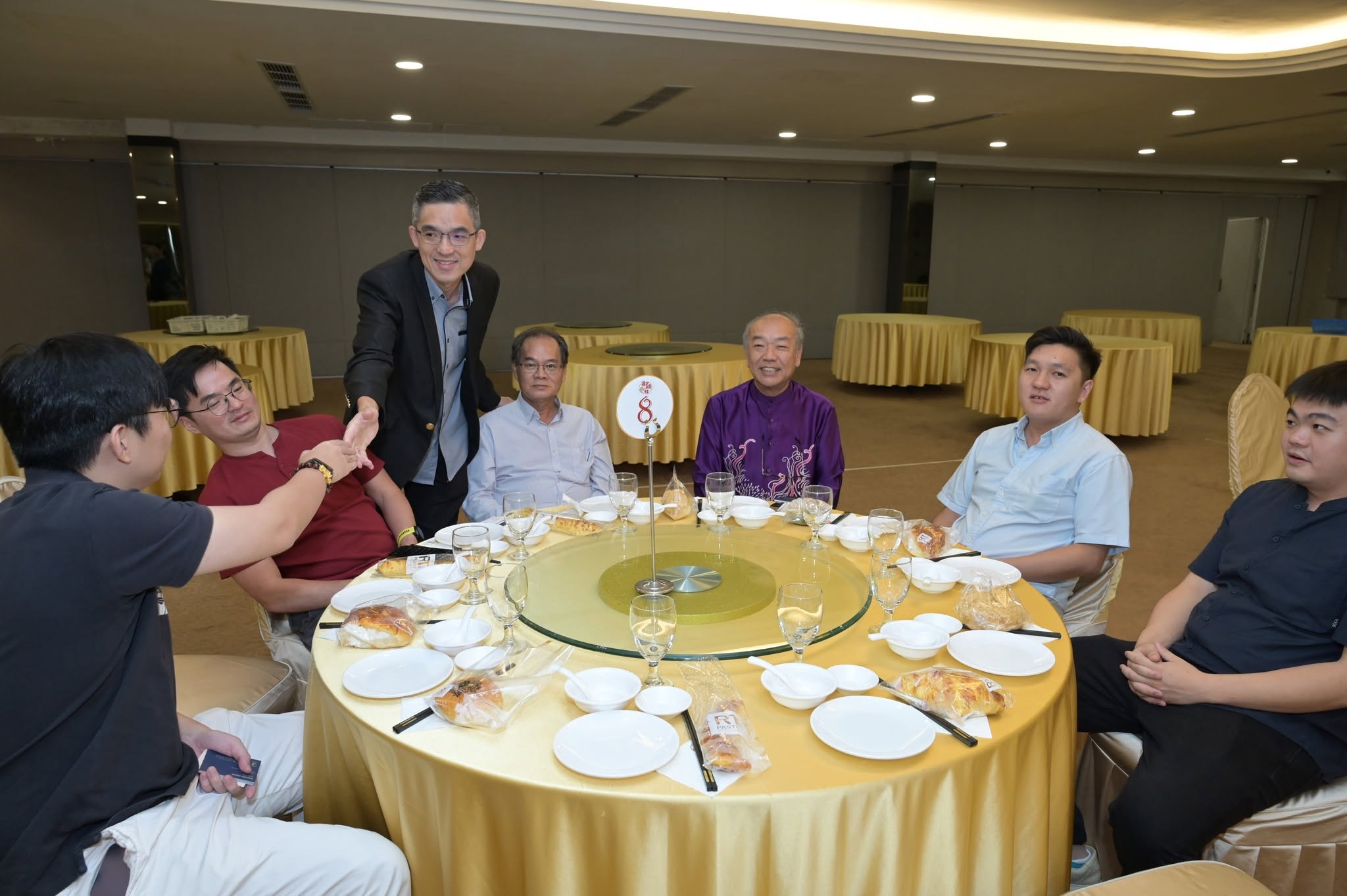 A speaker greeting members around a banquet table